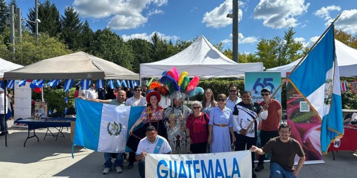 Stand promocional de Guatemala en el Festival Latino de Ottawa con artesanías, imágenes de destinos turísticos y muestra cultural.